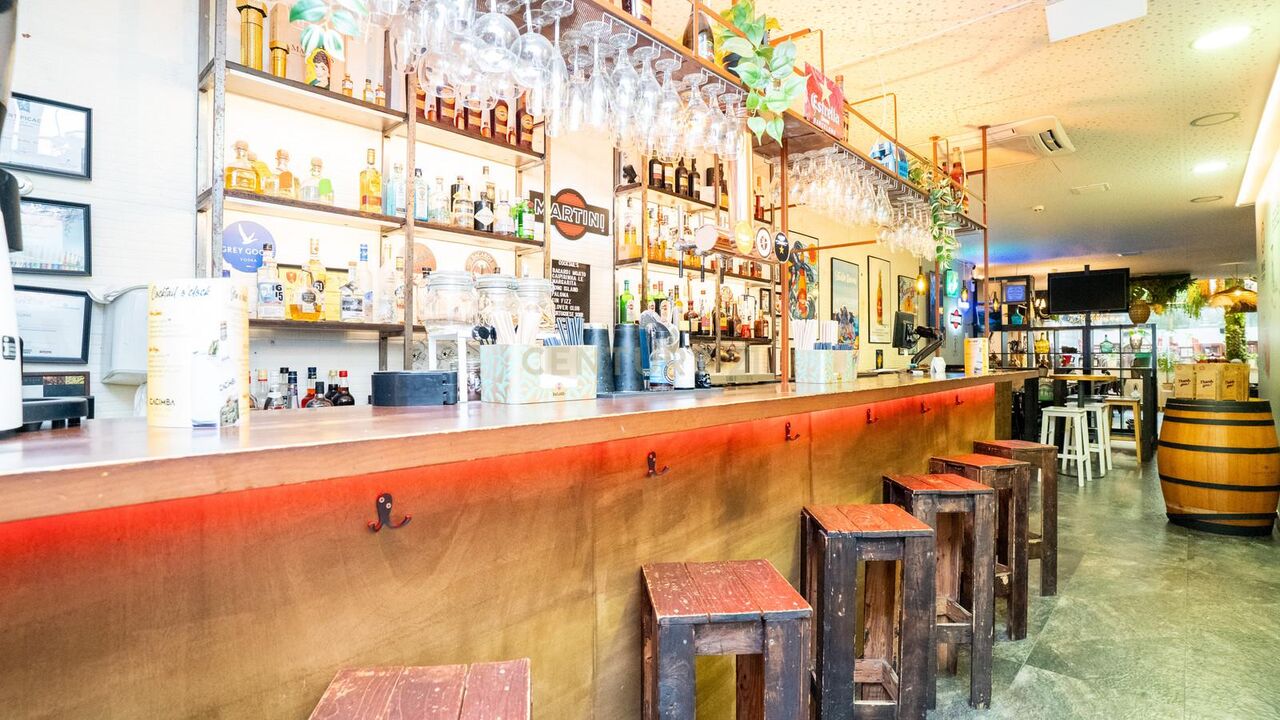 Wooden bar counter with stools and a back bar of bottles