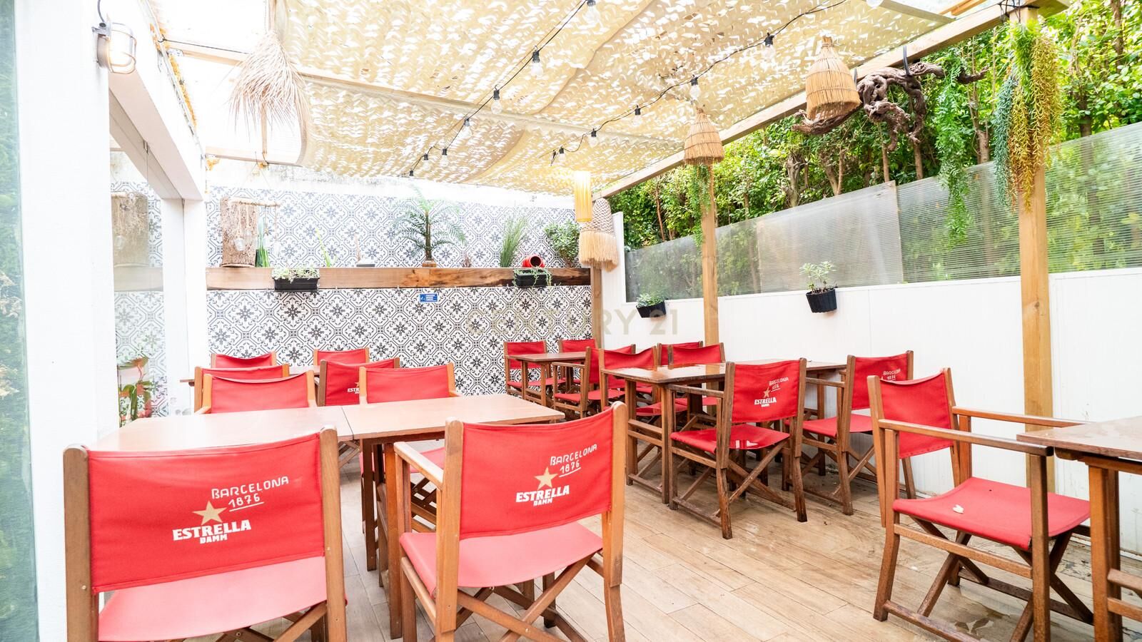 Covered terrace of Wine Hunters with red director chairs and wooden tables